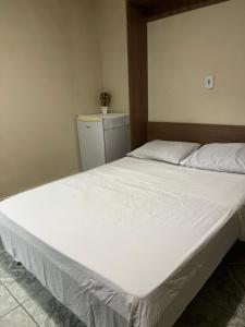 Un dormitorio con una gran cama blanca en una habitación. en Quarto suite em Caraguatatuba, en Caraguatatuba