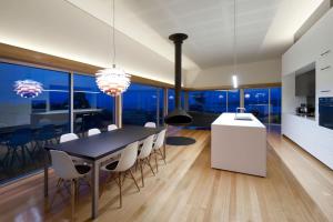 a dining room with a black table and white chairs at Marion Bay House, Luxury Retreat in Bream Creek
