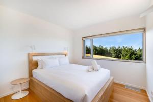 a bedroom with a bed and a large window at Marion Bay House, Luxury Retreat in Bream Creek