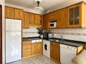a kitchen with wooden cabinets and a white refrigerator at La Cava en Isla - 5611 in Isla