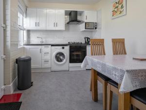 a kitchen with a washing machine and a table with chairs at 30 Marian Park - Luxury Townhouse in Buncrana