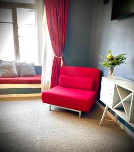 a red chair in a room with a window at Bavaria Boutique Hotel in Auckland