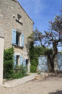 Saint-Gervasy玫瑰住宿加早餐旅馆的一栋有蓝色门的砖砌建筑和一棵树