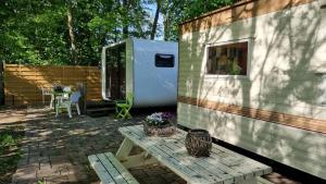 阿姆斯特丹City Farmer Farmyard Stays, Sleep Easy, Stay Rural, Explore Amsterdam的一辆绿白相间的拖车，旁边有一张野餐桌