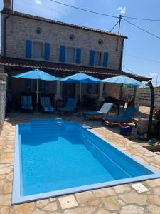 a swimming pool in front of a house with umbrellas at Villa Rafaela Umag in Umag
