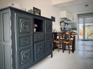 a large black cabinet in a kitchen with a table at Les Sardinières in Le Relecq-Kerhuon