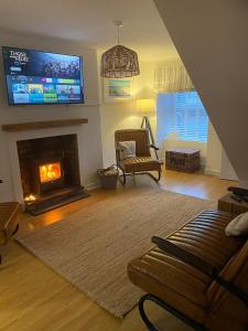 ein Wohnzimmer mit einem Sofa und einem Kamin mit einem TV in der Unterkunft Charming, stylish cottage, parking , large private Garden, well located for island highlights in Gaerwen