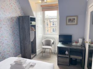a bedroom with a desk and a chair and a window at Alexander Guest House in Edinburgh