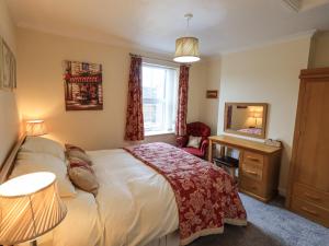 a bedroom with a bed and a desk and a mirror at Violey Cottage in Maryport