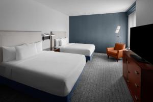 a hotel room with two beds and a flat screen tv at Courtyard by Marriott Santa Clarita Valencia in Valencia