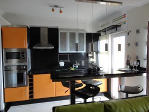 een keuken met een zwarte bar en oranje kasten bij Apartamento Raio de Sol in Caniço