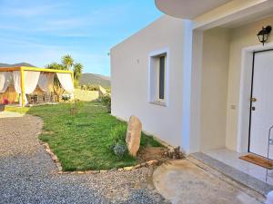 a white house with a door and a yard at Villa Mary Holiday Home Near Villasimius in Quartu SantʼElena