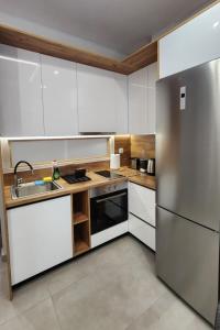 a kitchen with white cabinets and a stainless steel refrigerator at Four Suns Loft in Thessaloniki