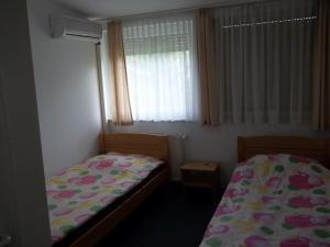 a small bedroom with two beds and a window at Gadányi Vendégház és Lovarda in Komló