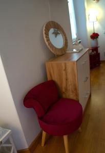 a red chair next to a dresser with a mirror at PortaTorre Suite, a Charming apartment in the Heart of Como, Free Private Parking, Air Conditioning & More! in Como