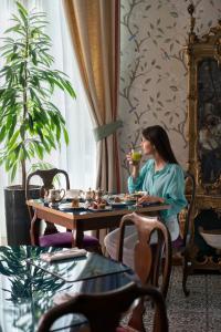 a woman sitting at a table with a cup of tea at Palace Hotel in Viareggio
