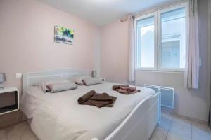 Un dormitorio con una cama blanca con toallas. en Appartement Améthyste Vals les bains, en Vals-les-Bains