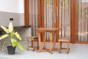 a wooden stool and two stools in front of a door at Ondrell Madiha in Matara
