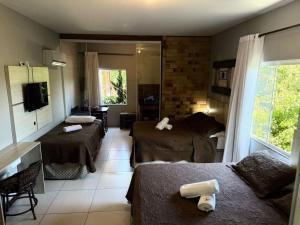 a hotel room with two beds and a living room at Pousada Carolina Apartamentos in Penha