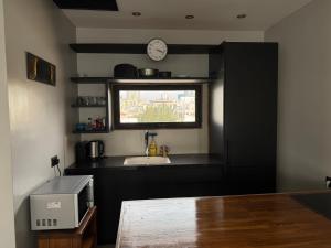 a kitchen with a sink and a clock on a window at Penthouse with Jacuzzi,BBQ 2mn from sea Or Hakerem in Tel Aviv