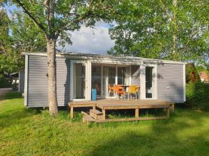 a small house with a deck and a table at Camping Pré Vologne in Granges-sur-Vologne