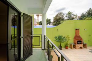 a balcony with a green wall and a brick fireplace at Suíte privativa 5 minutos metrô com Piscina e churrasqueira in Sao Paulo