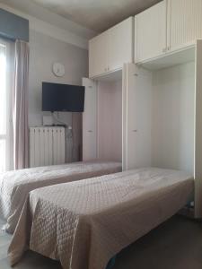 a bedroom with two beds with white cabinets and a tv at CadiLina in Ceriale