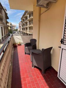 a patio with chairs and tables on a balcony at Living Room Orlando in Corigliano Calabro