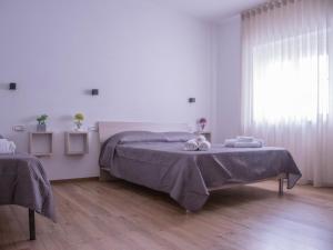 a white bedroom with a bed with a gray blanket at Modern House Monolocali in Le Castella