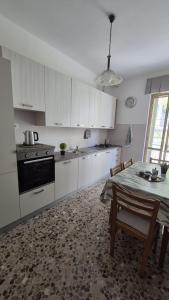 a kitchen with white cabinets and a table and a dining room at Soffio Marino in Polignano a Mare