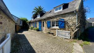 a stone house with blue windows and a palm tree at TI Soul - Calme- Authentique in Crozon