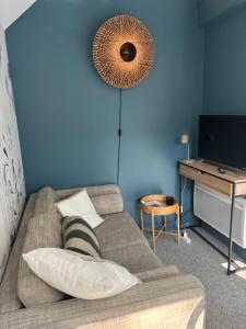 a living room with a couch and a blue wall at Gîte du Cap Romain in Bernières-sur-Mer