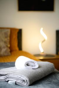 a stack of towels on a bed with a lamp at Modern house , Perfect for business trip & Families holiday or working proffesionals-5 min from M1 J25 , 500MB Wi-Fi , Netflix , Fully equiped kitchen , Asda supermarket 5 min walk , Free Secure parking with CCTV ,available monthly deals in Nottingham
