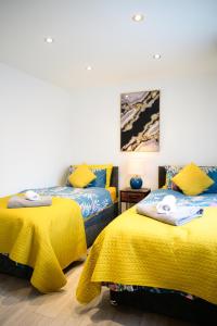 a bedroom with two beds with yellow sheets and a painting at Modern house , Perfect for business trip & Families holiday or working proffesionals-5 min from M1 J25 , 500MB Wi-Fi , Netflix , Fully equiped kitchen , Asda supermarket 5 min walk , Free Secure parking with CCTV ,available monthly deals in Nottingham