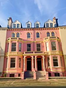 a large pink building with stairs in front of it at The Palace Villas - Location, Luxury and Space in Eastbourne