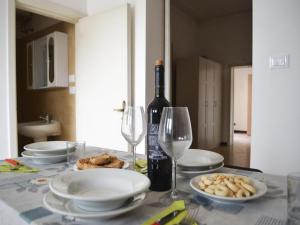 einen Tisch mit Tellern und Gläsern sowie eine Flasche Wein in der Unterkunft TSUKY Holiday Home in Torre dellOrso in Torre dell'Orso