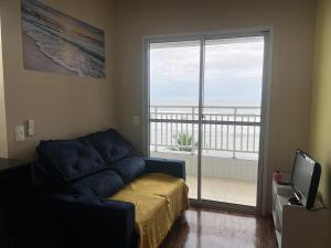 a living room with a couch and a large window at Refúgio do Aconchego Frente Praia Ocean Club in Mongaguá
