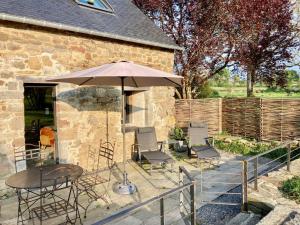 a patio with a table and chairs and an umbrella at Le Nid de la Breizhidence in Combourg