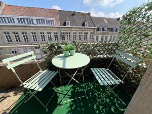 a table and two chairs on a balcony with a building at « stef one « centre ville 2 chambres 3 voyageurs in Valenciennes