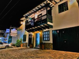 a building with a balcony and a car on a street at HOTEL El CORZO DE LA VILLA in Villa de Leyva
