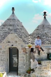 a woman sitting on the ledge of a brick building at Trulli di Titti - Luxury Country House in Castellana Grotte
