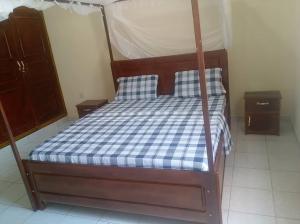 a bed with a blue and white checkered mattress at Villa ZEIMET in Bujumbura
