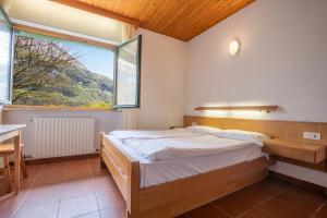 a bedroom with a bed and a large window at Al Trovante - Gardaslowemotion in Tenno +32 photos
