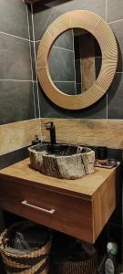 a bathroom sink with a mirror and a basket at Les Châtaigniers Gîtes du Mas Haut in Saint-Jean-du-Gard