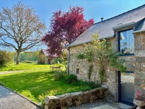 an old stone house with a garden in front of it at Le Nid de la Breizhidence in Combourg