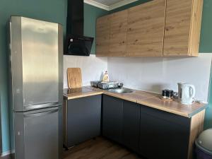 a kitchen with a stainless steel refrigerator and wooden cabinets at Loft&Cozy in Zgorzelec