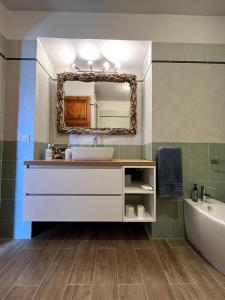 Un baño con lavabo, espejo y bañera. en Il Fenicottero - Cozy apartment with view, en Porto Santo Stefano