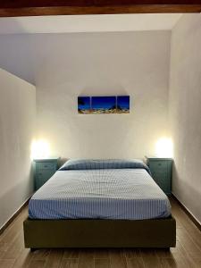 Un dormitorio con una cama y dos luces en la pared. en Il Fenicottero - Cozy apartment with view, en Porto Santo Stefano