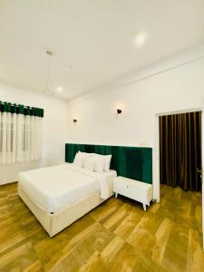 Cama blanca grande en habitación con suelo de madera en Ambuluwava Eco Resort, en Gampola