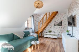 a living room with a green couch and a staircase at Apartament Górska Przystań - blisko dworca PKP, w spokojnej okolicy by Apartamenty w Karkonoszach in Karpacz